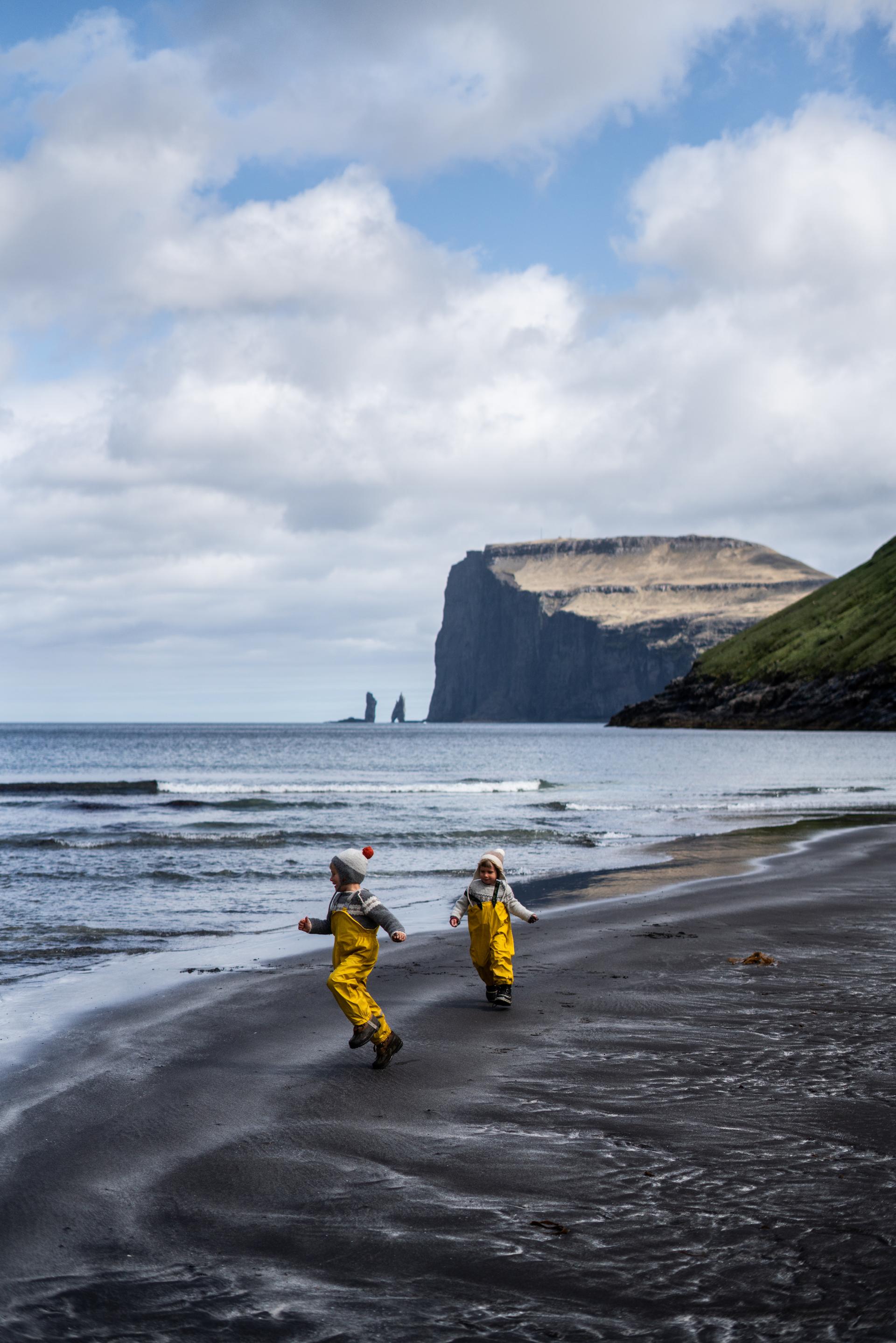 Thumbnail of - Children in yellow overalls playing on the sand beach of Tjornuvik, Tjørnuvík, Faroe Islands