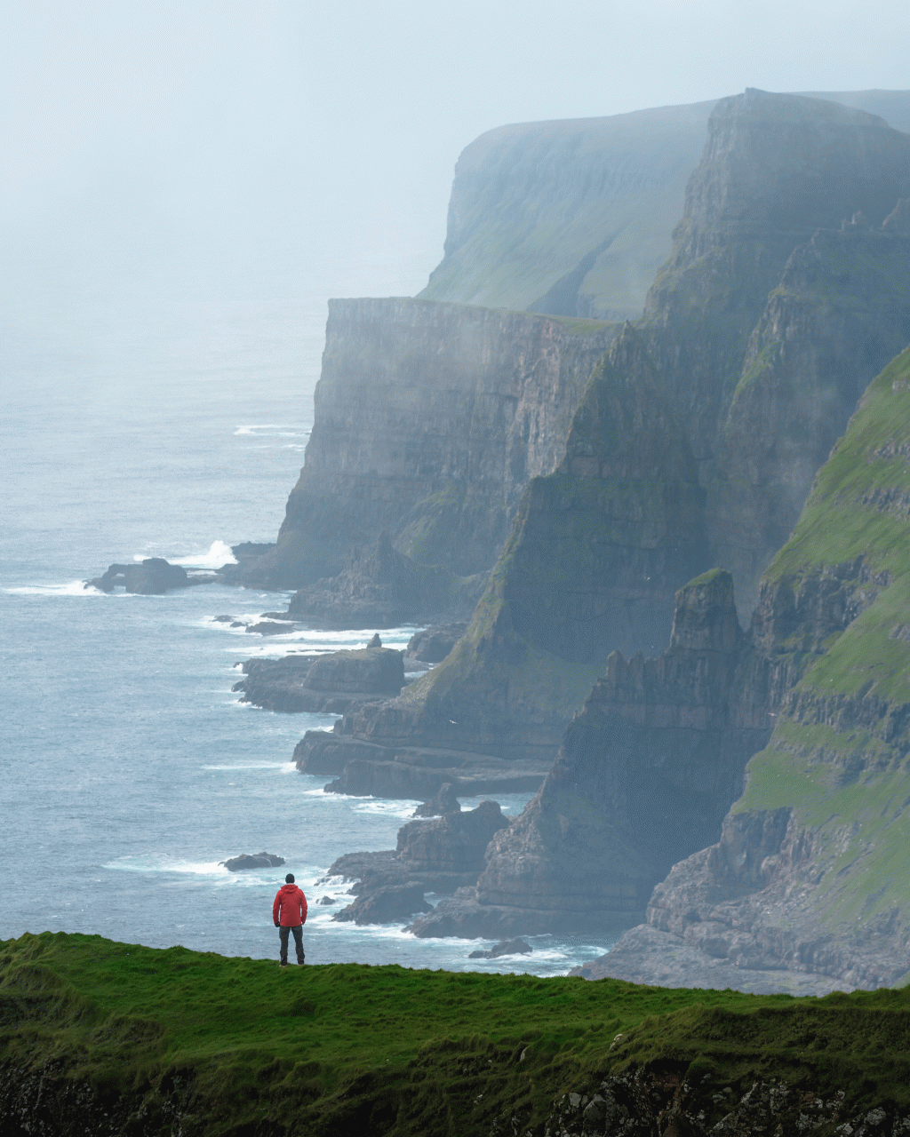 View of man at Beinisvørð on Suðuroy with breathtaking view of cliff side