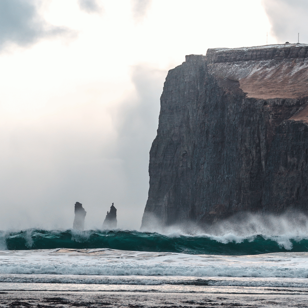 Strong ocean waves bursting against stunning rock formations 
also a legend known as, Risin og Kellingin, in the Faroe Islands